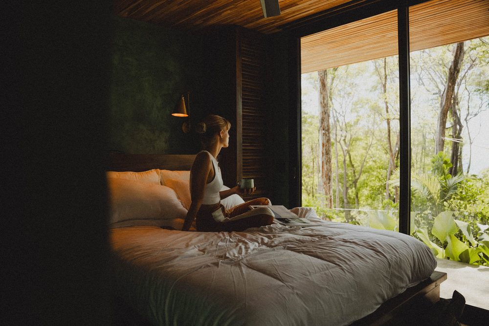 Meditation beside floor-to-ceiling jungle windows
